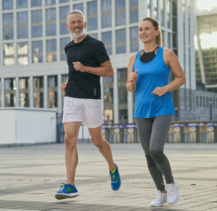 A fit couple jogging in front of a building, enjoying a healthy outdoor activity together.
